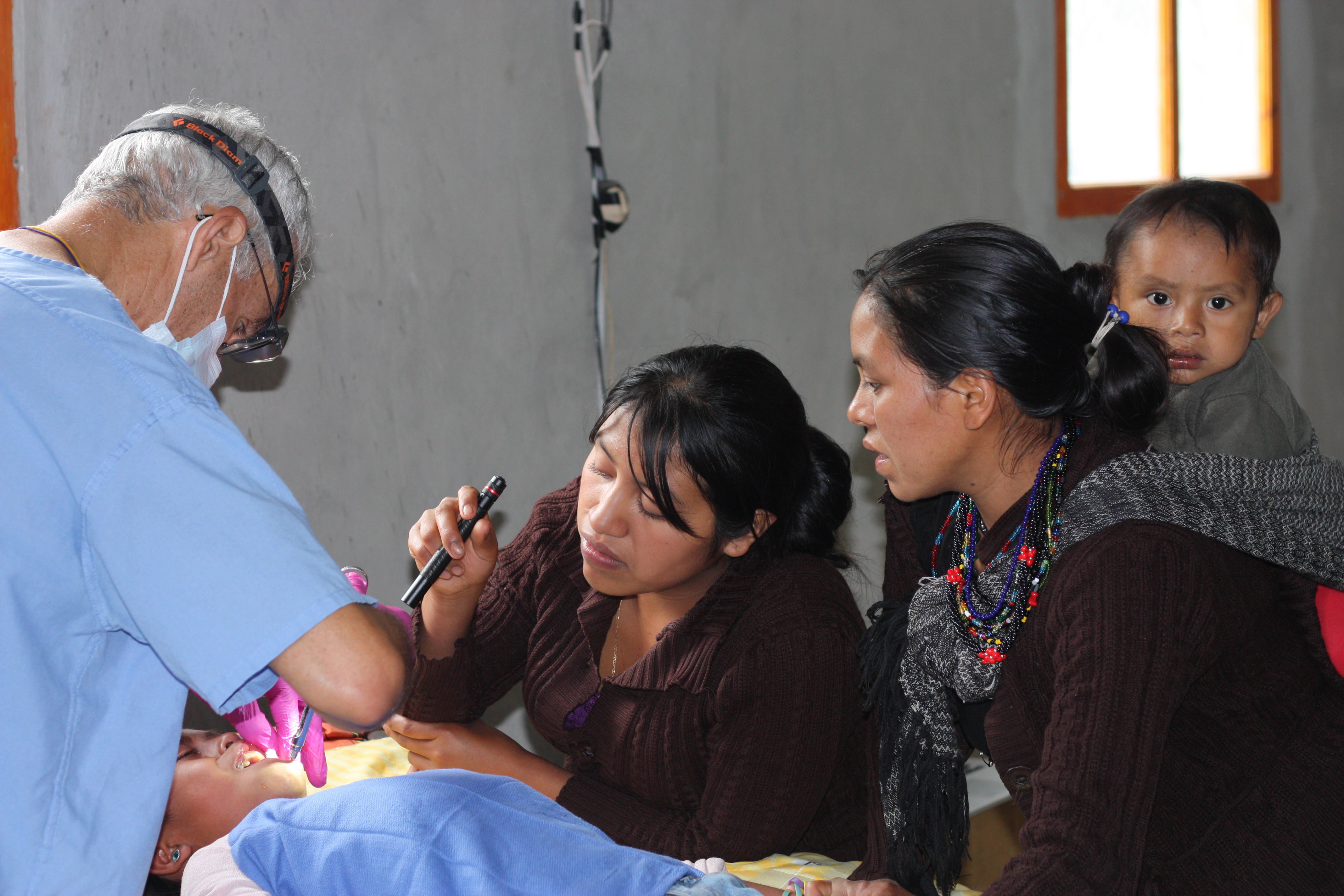 Dr. Manteris extracts decayed teeth from a young child as mother looks on