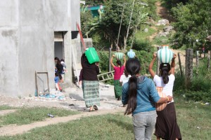 village women bearing water to fill tank